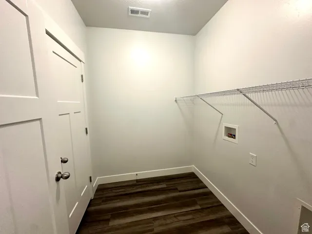 Clothes washing area featuring dark wood-style floors, visible vents, baseboards, washer hookup, and laundry area