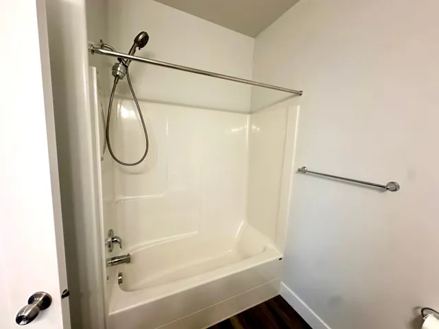 Bathroom with baseboards, wood finished floors, and shower / bath combination