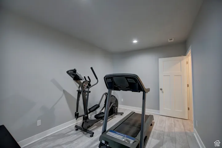 Exercise room featuring baseboards, light wood-type flooring, and recessed lighting