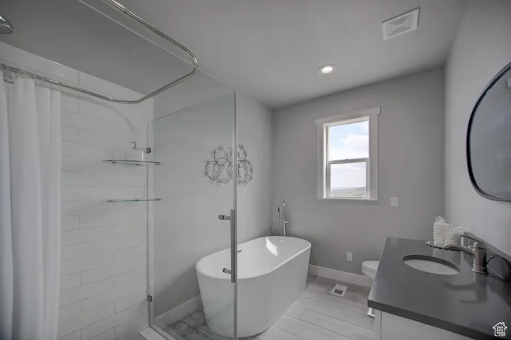 Bathroom featuring visible vents, a soaking tub, vanity, and tiled shower
