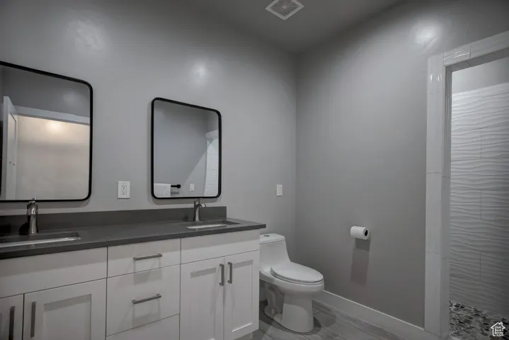 Full bath featuring toilet, double vanity, a sink, and visible vents