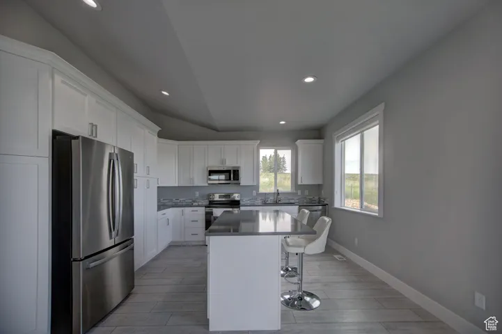 Kitchen with a breakfast bar, recessed lighting, a center island, and appliances with stainless steel finishes