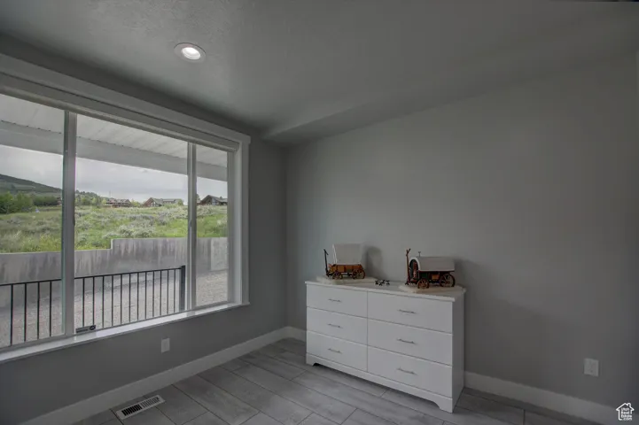 Bedroom with wood finish floors, a textured ceiling, visible vents, and baseboards