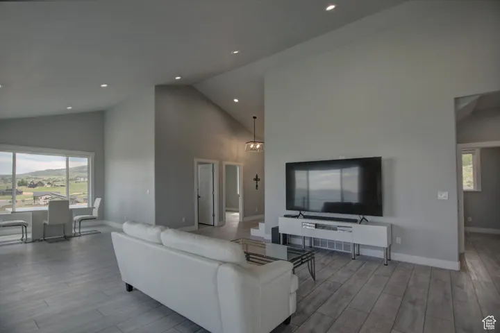 Living room featuring wood finished floors, recessed lighting, high vaulted ceiling, and baseboards