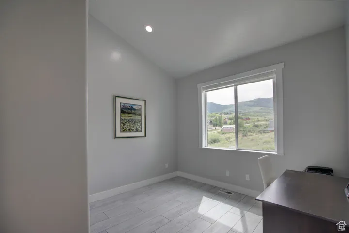Spare room featuring lofted ceiling, visible vents, baseboards, wood finish floors, and a mountain view