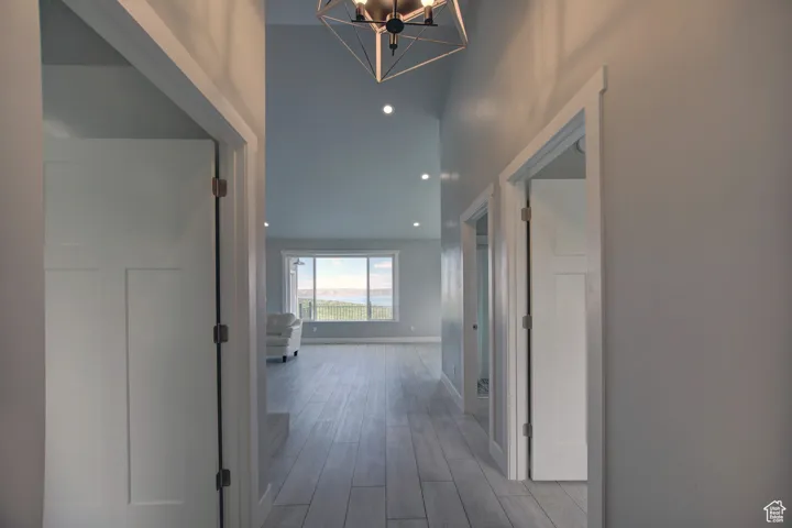 Hallway with a notable chandelier, wood finished floors, and baseboards