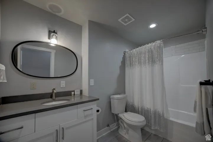 Full bath featuring recessed lighting, vanity, shower / bath combo with shower curtain, toilet, and visible vents