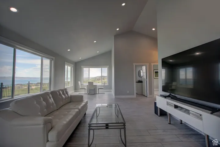Living room with recessed lighting, high vaulted ceiling, wood finished floors, and baseboards