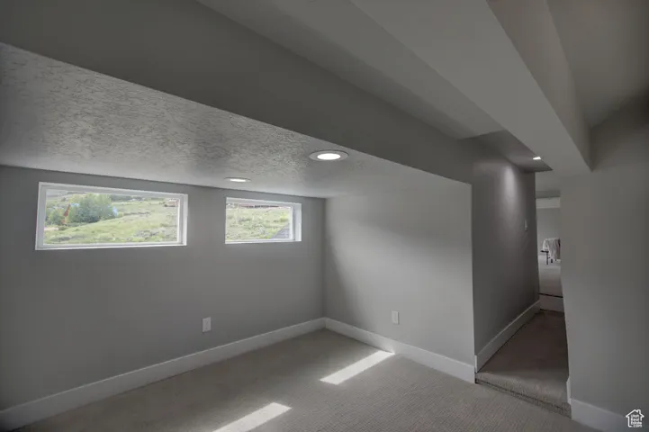 Below grade area with recessed lighting, a textured ceiling, carpet flooring, and baseboards
