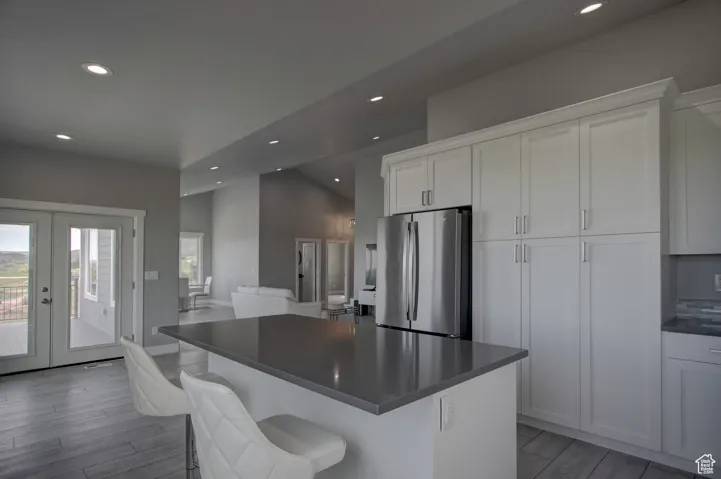Kitchen with white cabinets, dark countertops, freestanding refrigerator, recessed lighting, and french doors