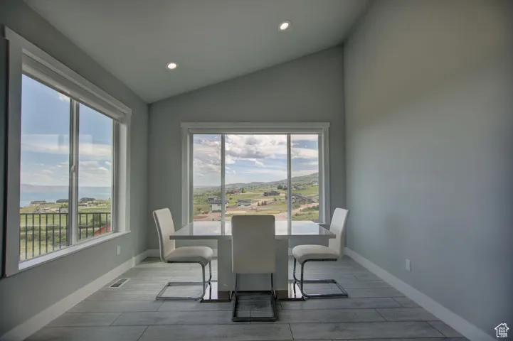 Dining room featuring wood tiled floor, visible vents, baseboards, recessed lighting, and vaulted ceiling