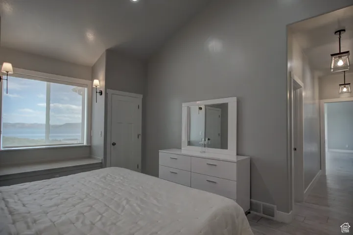 Bedroom featuring visible vents, vaulted ceiling, wood finished floors, and baseboards