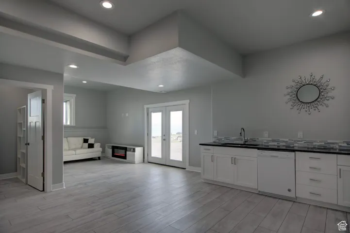 Kitchen featuring a sink, dark countertops, open floor plan, dishwasher, and light wood finished floors