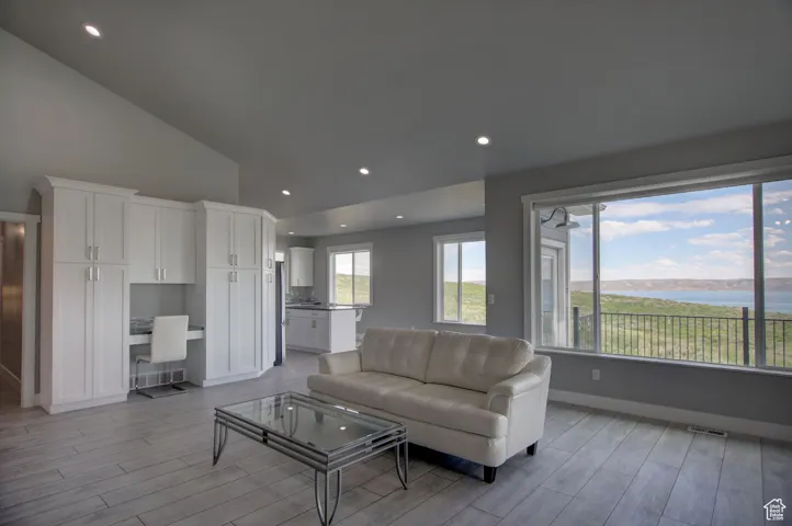 Living room with light wood-type flooring, recessed lighting, high vaulted ceiling, and baseboards