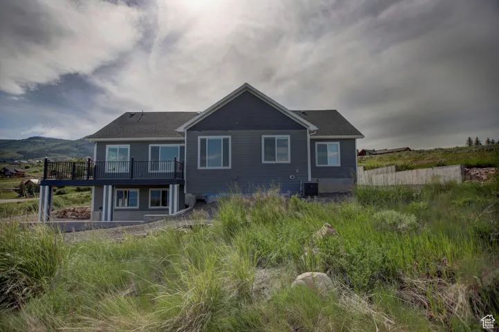 Back of house featuring central air condition unit and a wooden deck