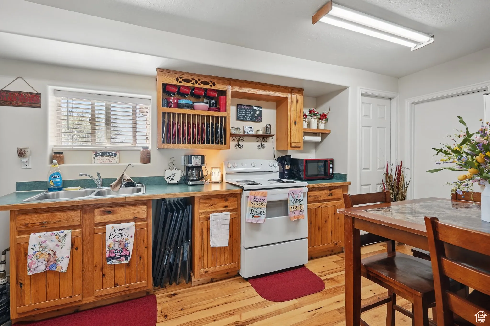 Kitchen with open shelves, brown cabinets, a sink, light wood-type flooring, and white electric range