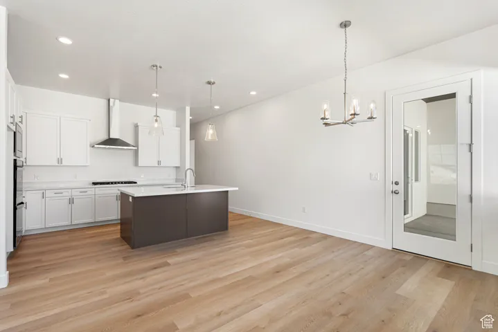 Kitchen featuring light countertops, a chandelier, light wood-type flooring, white cabinetry, and recessed lighting