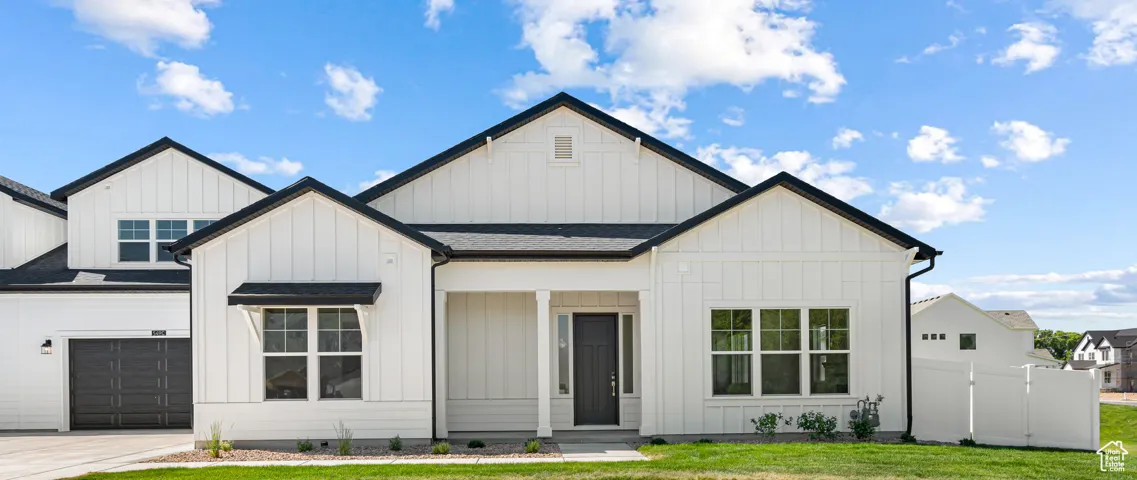 Modern farmhouse with board and batten siding, an attached garage, driveway, and roof with shingles