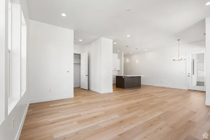 Unfurnished living room with a chandelier, light wood-style floors, and recessed lighting