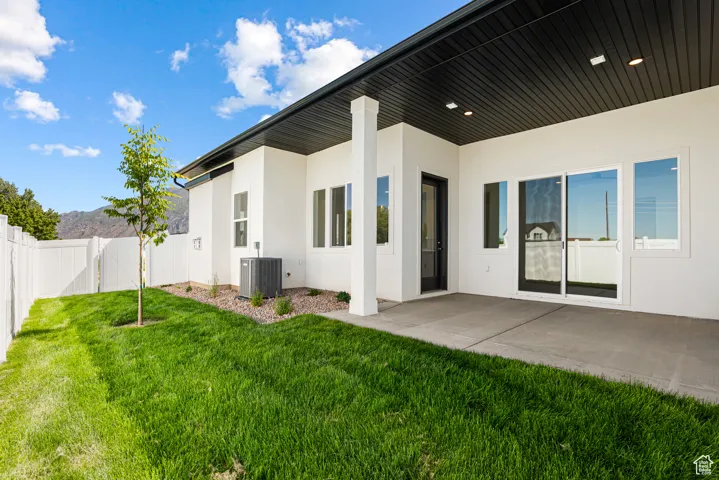 Rear view of property featuring stucco siding, a fenced backyard, and a patio