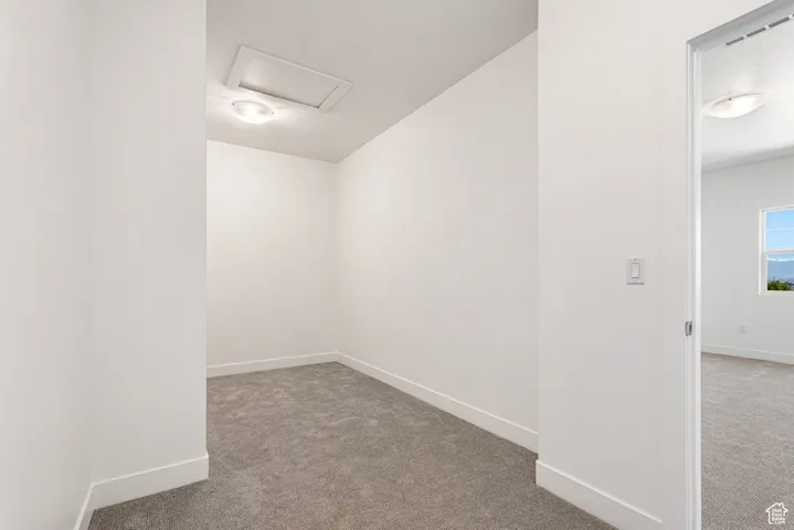 Empty room featuring carpet flooring and attic access