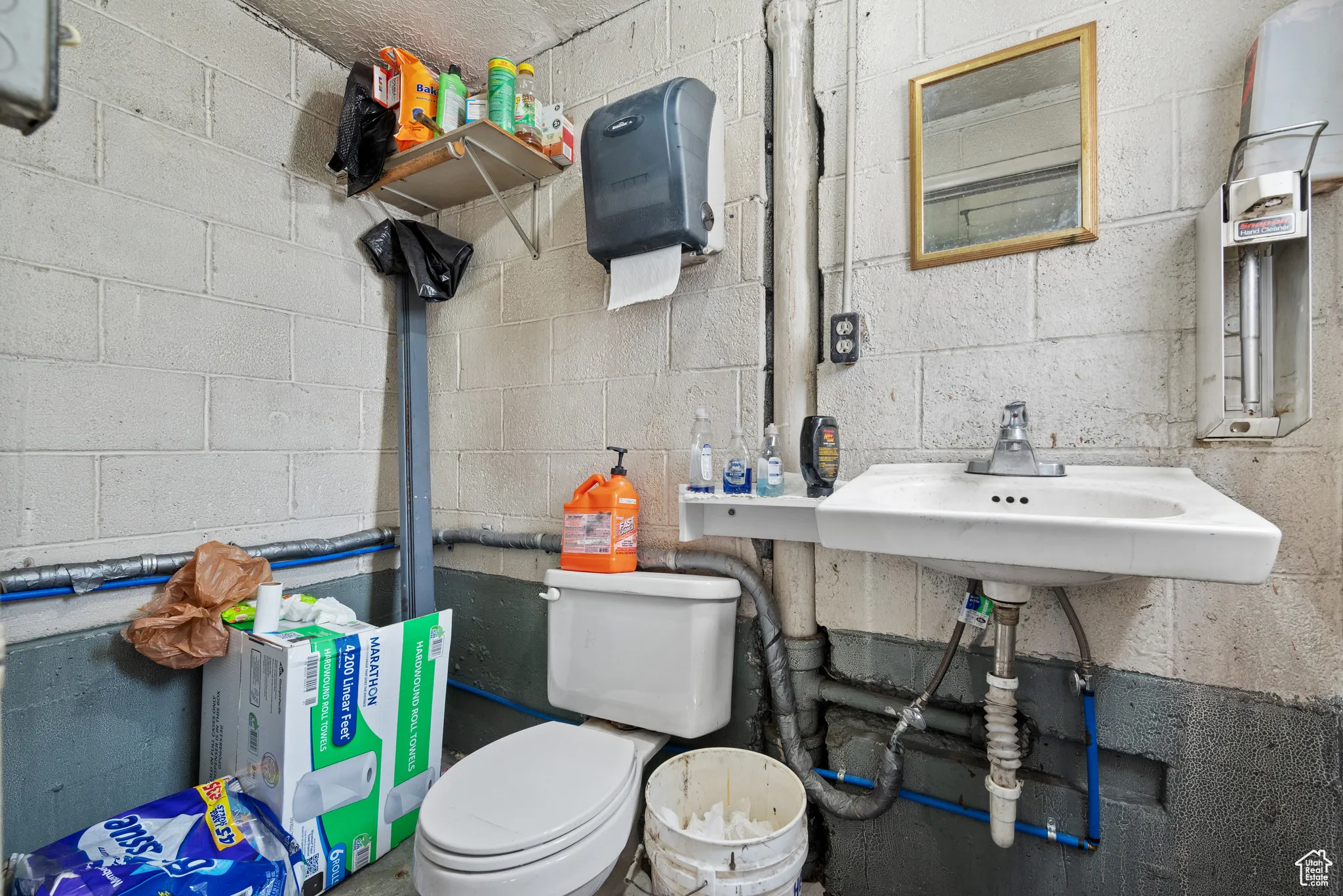Bathroom featuring toilet, a sink, and concrete block wall