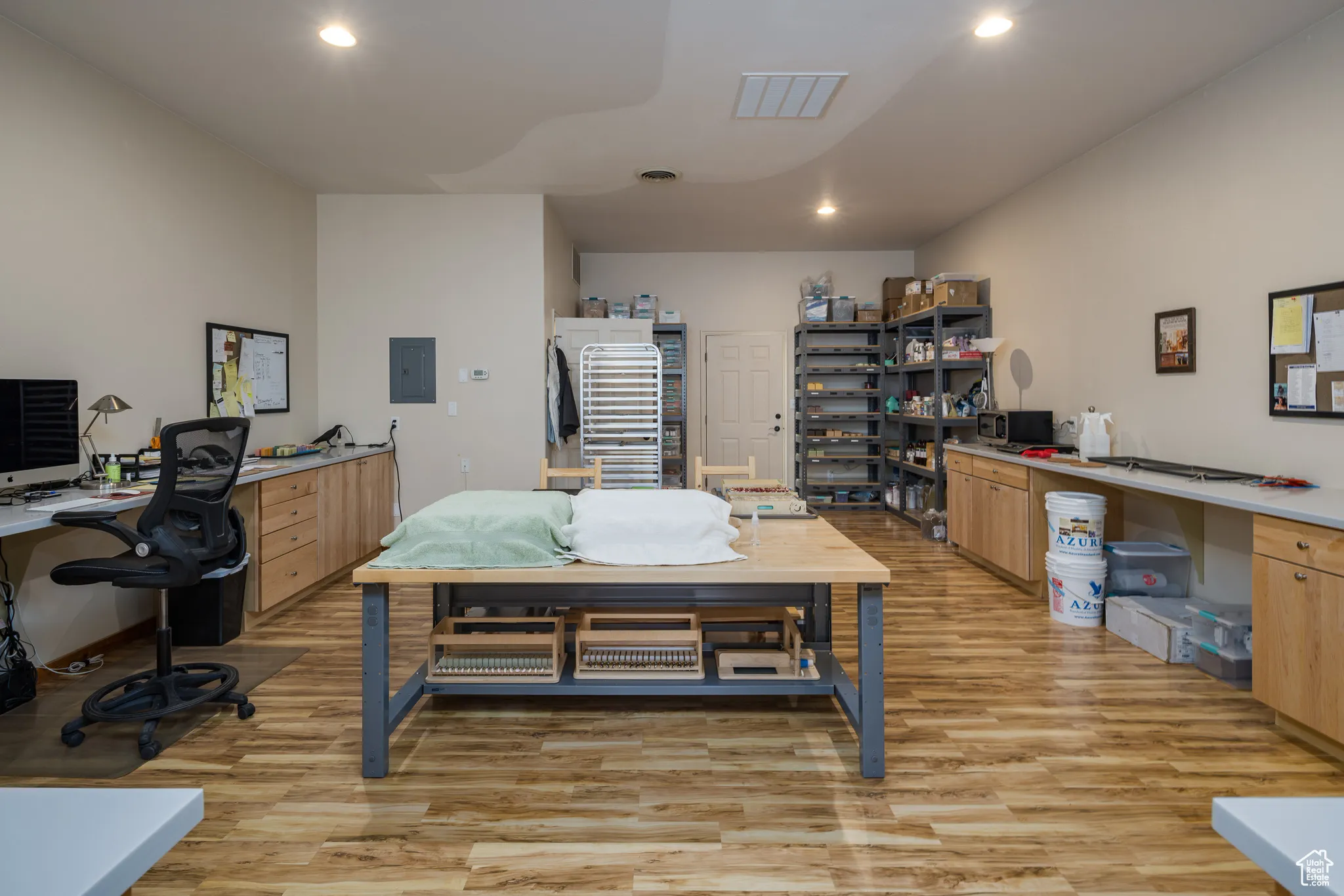 Office space featuring recessed lighting, electric panel, visible vents, and light wood finished floors