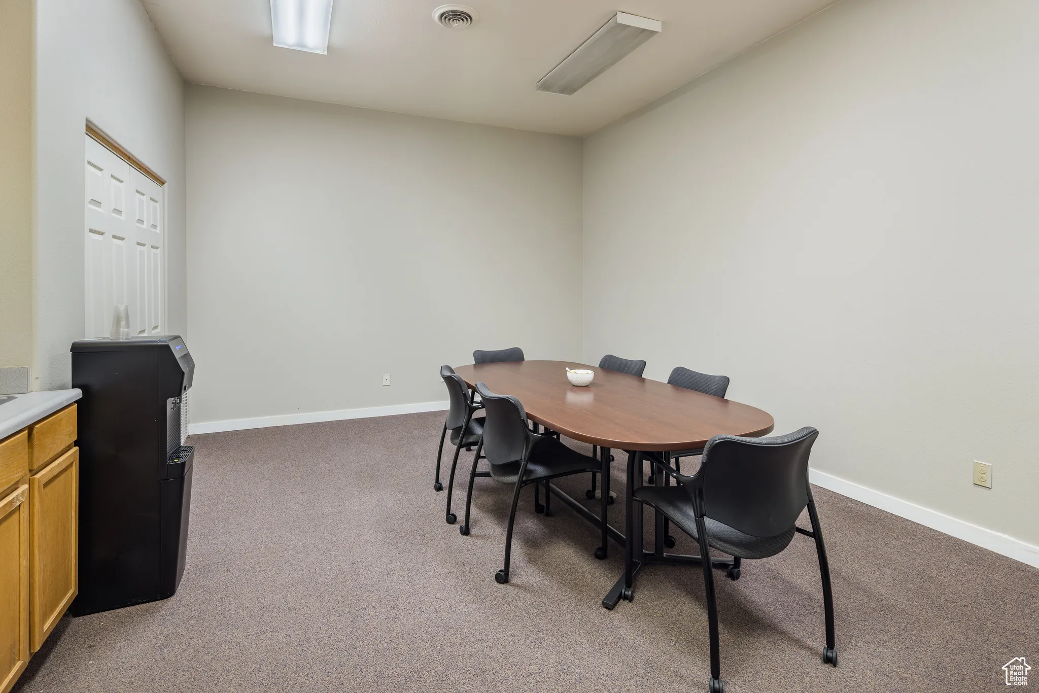Dining space featuring dark colored carpet, visible vents, and baseboards