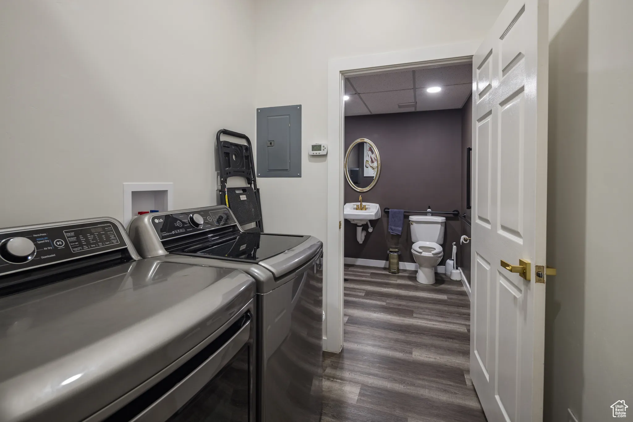 Clothes washing area featuring electric panel, a sink, dark wood-style flooring, separate washer and dryer, and laundry area