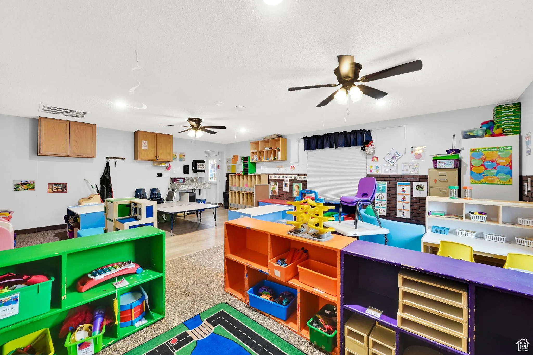 Playroom with a textured ceiling, visible vents, and a ceiling fan