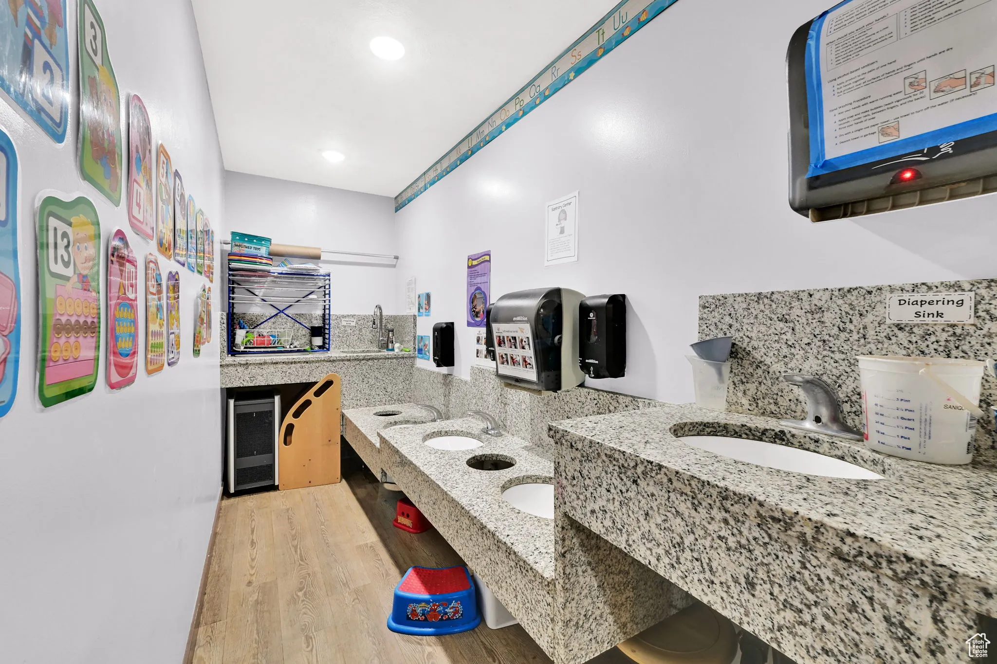 Bathroom with recessed lighting, wine cooler, tasteful backsplash, double sink, and wood finished floors