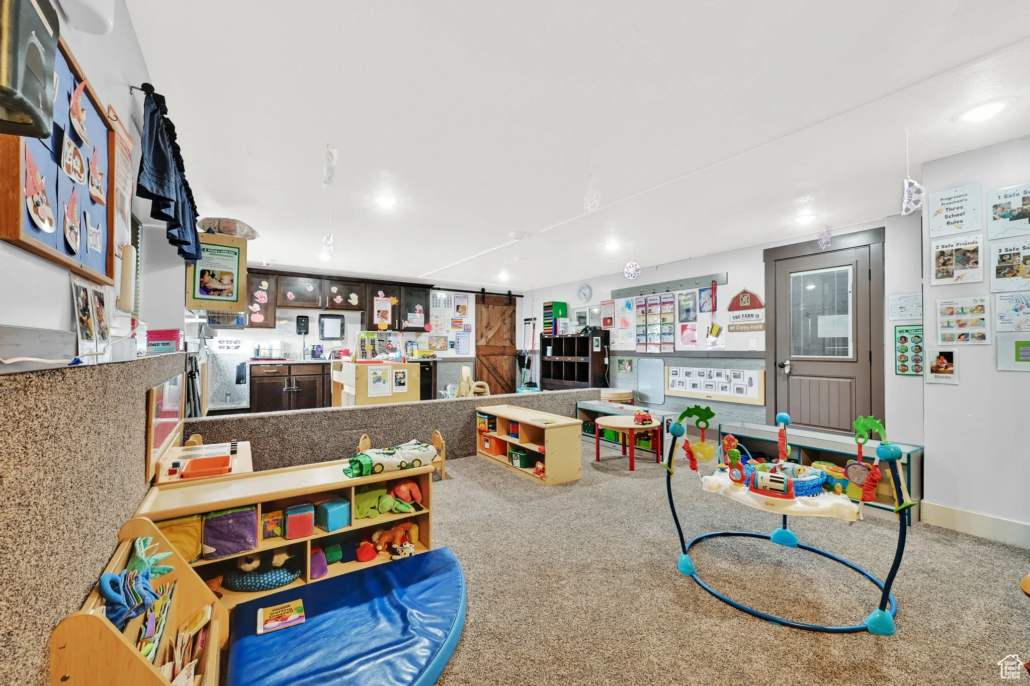 Recreation room with a barn door, recessed lighting, and carpet flooring