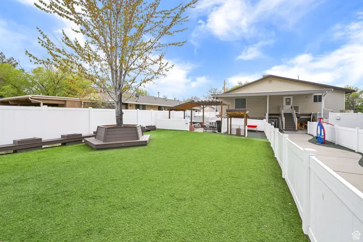 View of yard featuring outdoor lounge area, a deck, a fenced backyard, and a jacuzzi