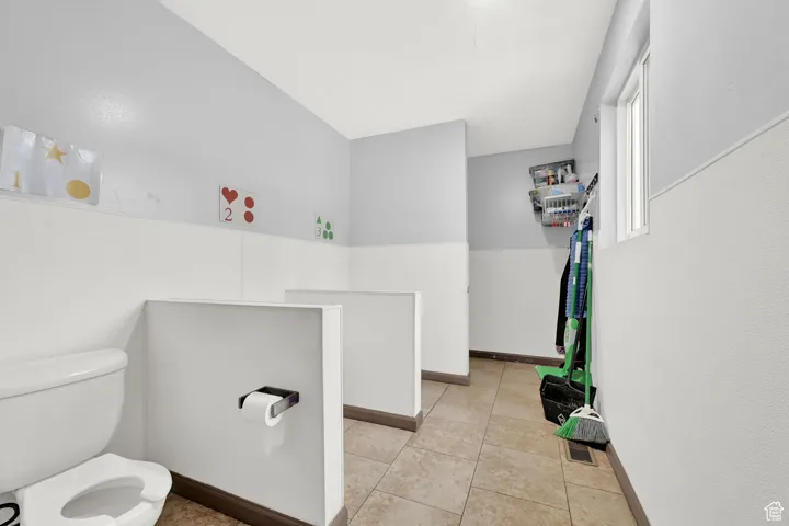 Bathroom featuring toilet, tile patterned flooring, and baseboards
