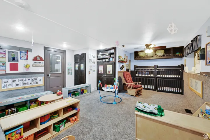 Recreation room with a ceiling fan and carpet floors