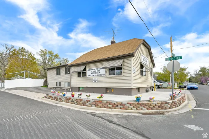 View of front of property with a chimney, a shingled roof, and fence