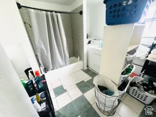 Bathroom featuring tile patterned floors, washer / dryer, and shower / bath combination with curtain