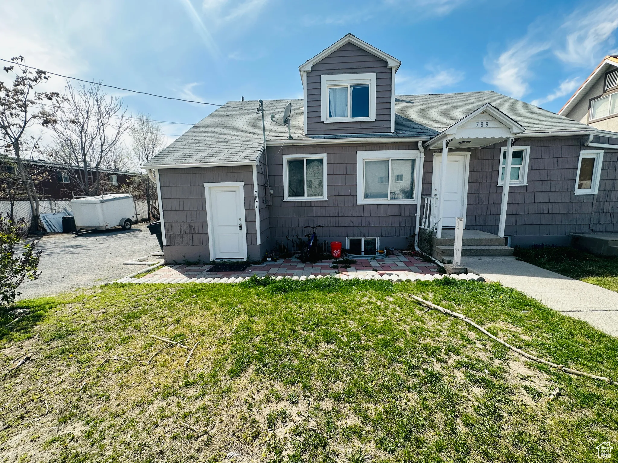 View of front of home featuring a patio, a front yard, and a shingled roof