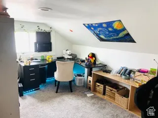 Carpeted home office with lofted ceiling