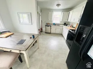 Kitchen with light floors, light countertops, dishwasher, gas stove, and white cabinetry