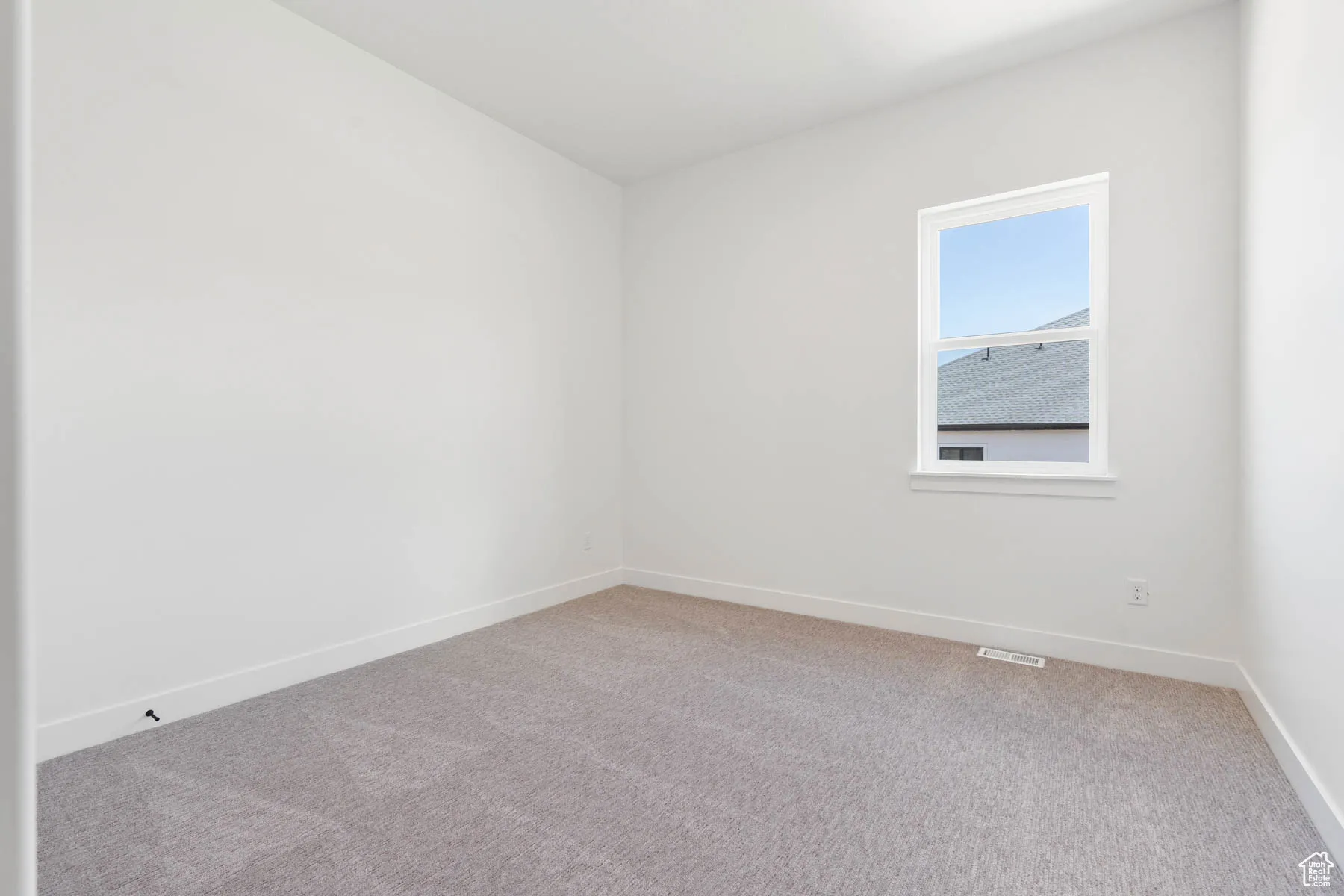 Spare room featuring baseboards, visible vents, and light carpet