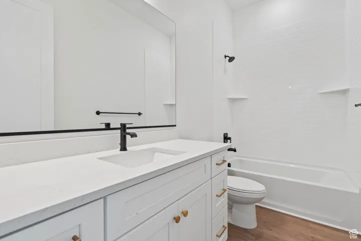 Full bathroom featuring vanity, toilet, wood finished floors, and shower / washtub combination