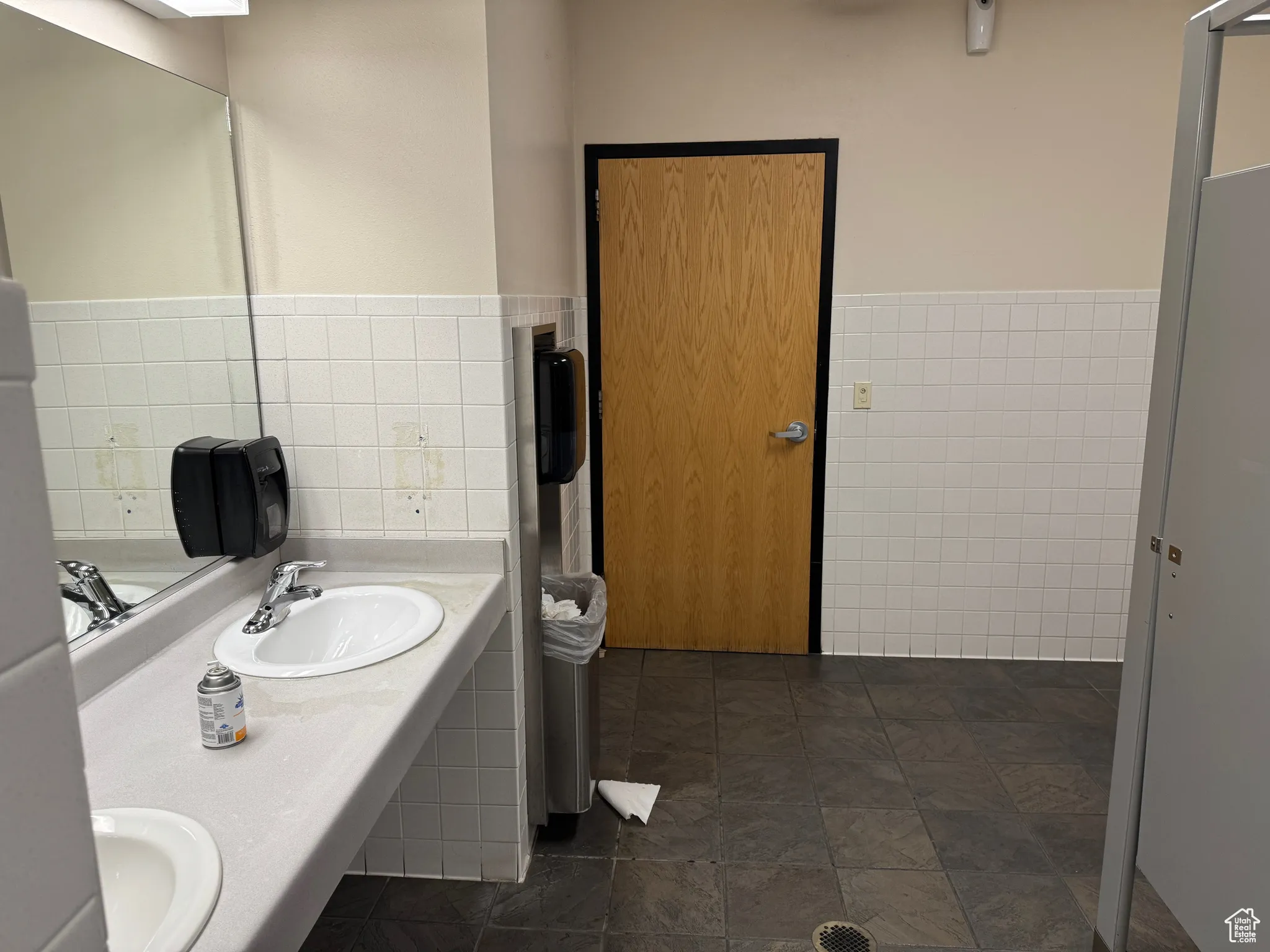 Full bath with a sink, tile walls, and a wainscoted wall