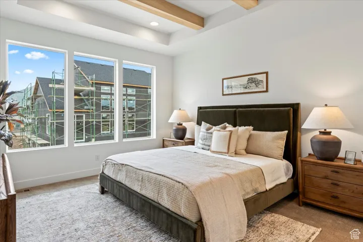 Bedroom with carpet floors, baseboards, and beam ceiling