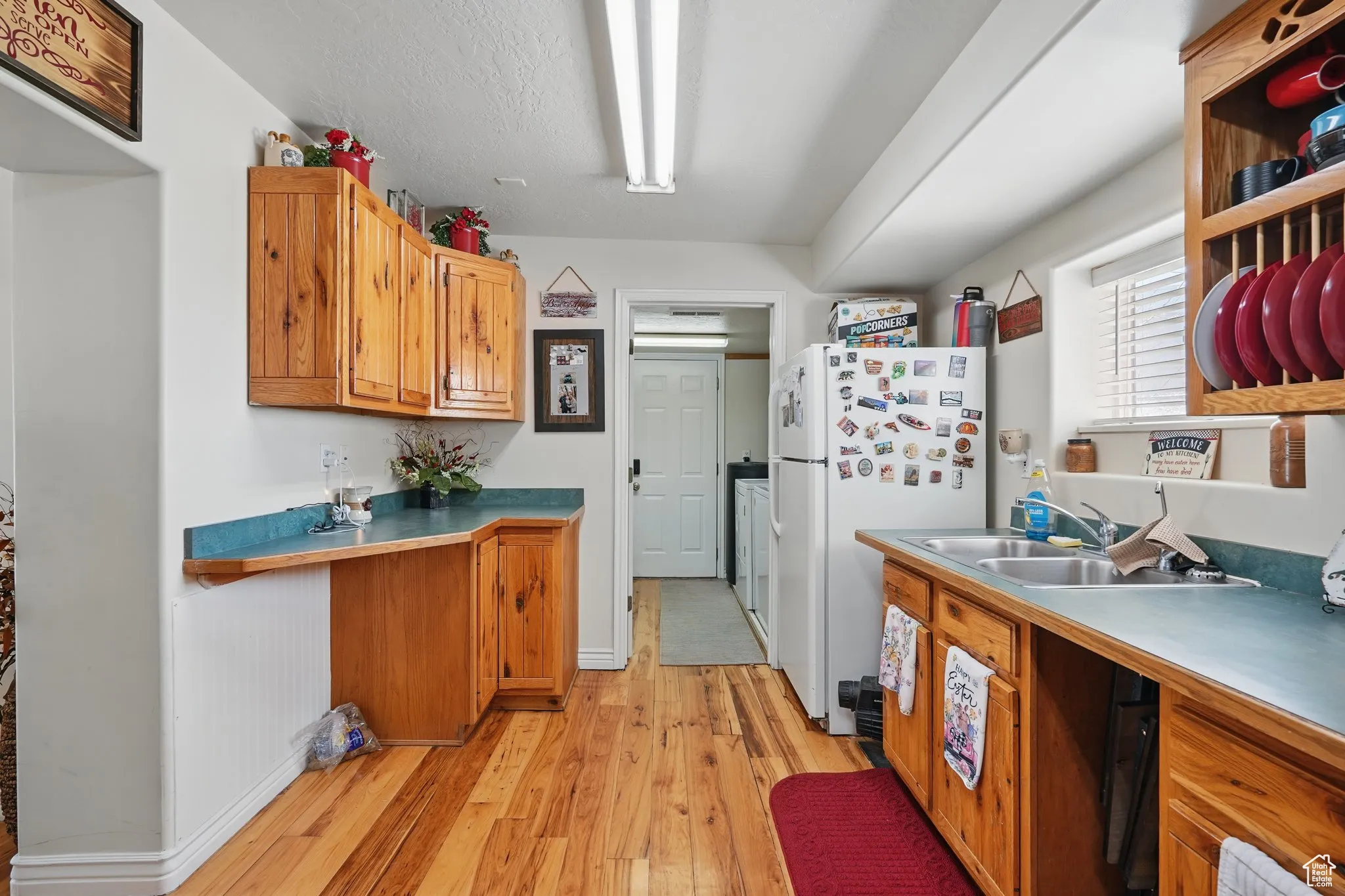 Kitchen featuring brown cabinets, a sink, freestanding refrigerator, baseboards, and light wood-type flooring