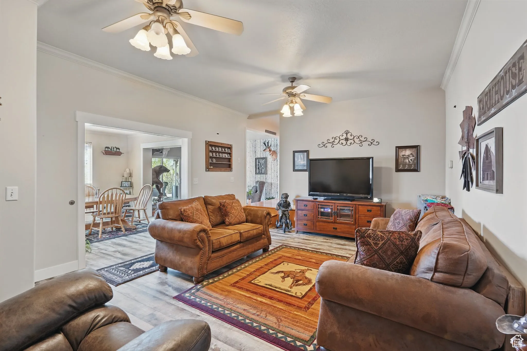 Living room with crown molding, light wood finished floors, and ceiling fan