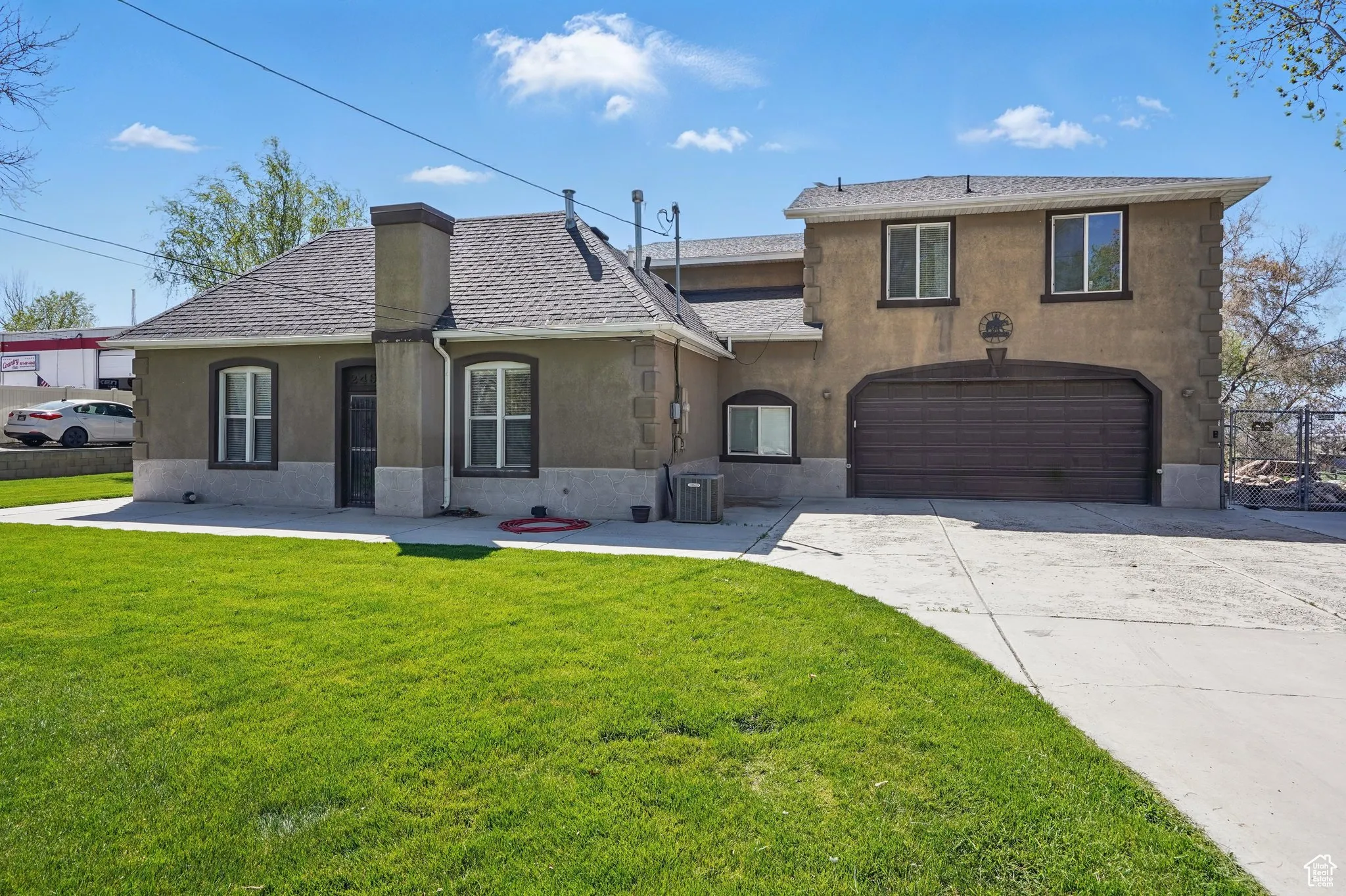 View of front of home featuring a garage, a front lawn, central AC, stucco siding, and driveway
