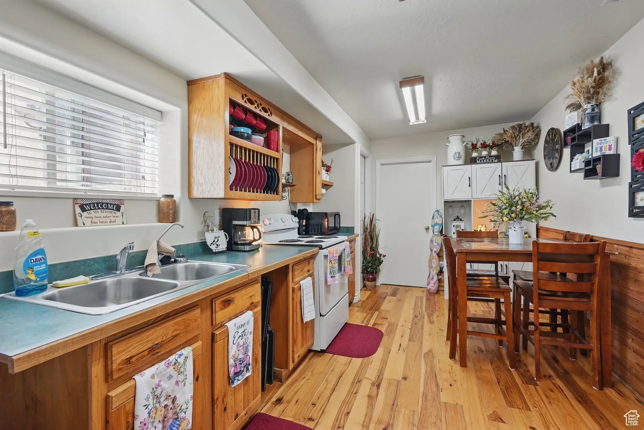 Kitchen with a sink, white range with electric stovetop, open shelves, and light wood finished floors