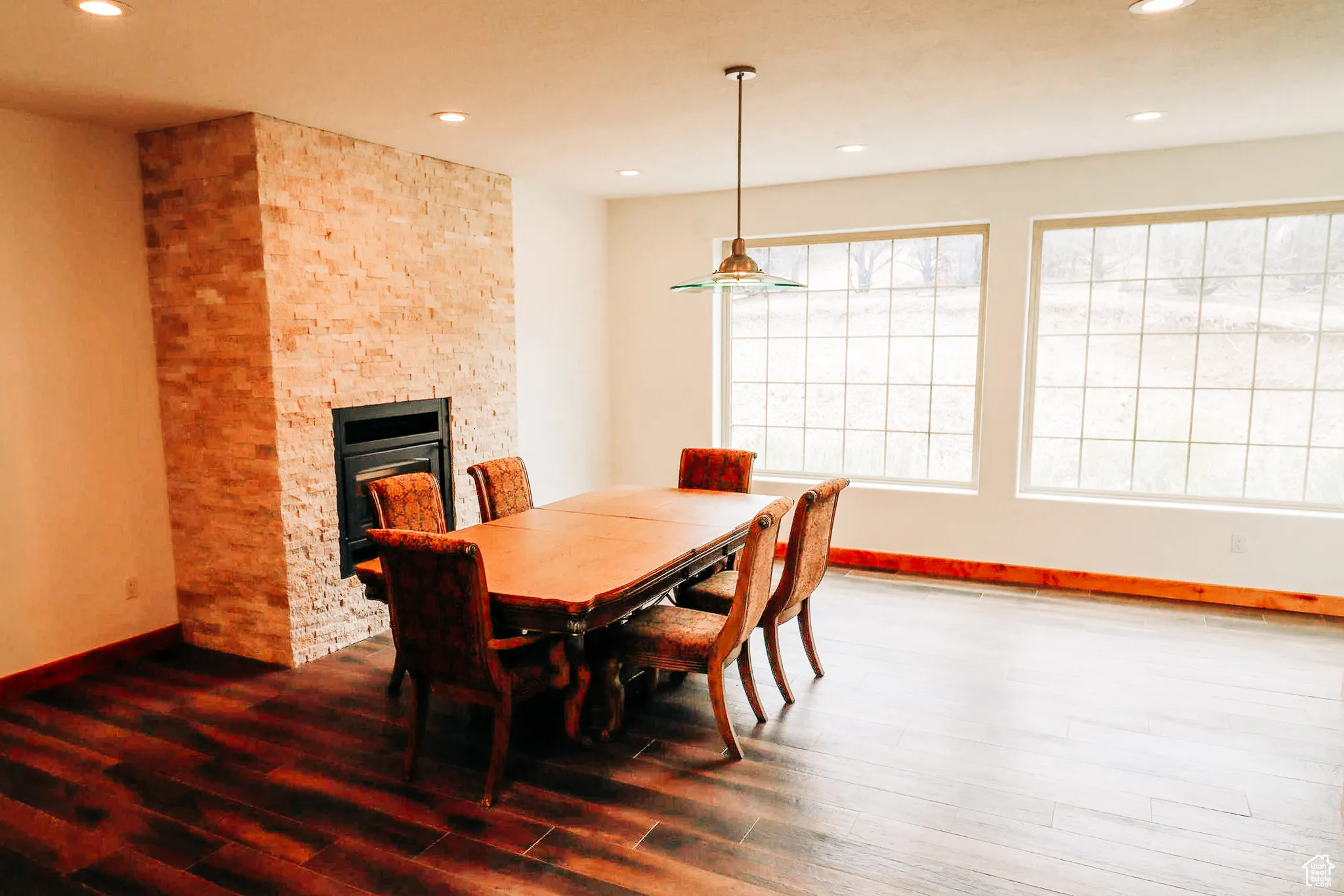 Dining space featuring a stone fireplace, recessed lighting, and dark wood finished floors