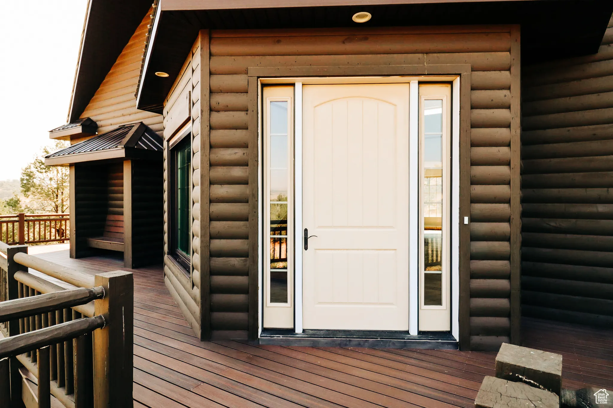 Entrance to property with faux log siding and a deck